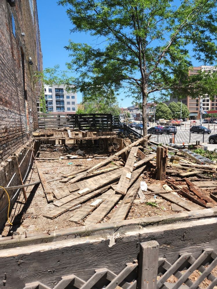 A pile of wood is sitting in front of a building under construction.