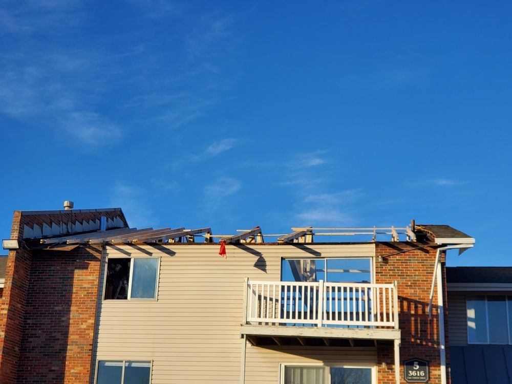 A house with a balcony and a roof that has been damaged by a storm.