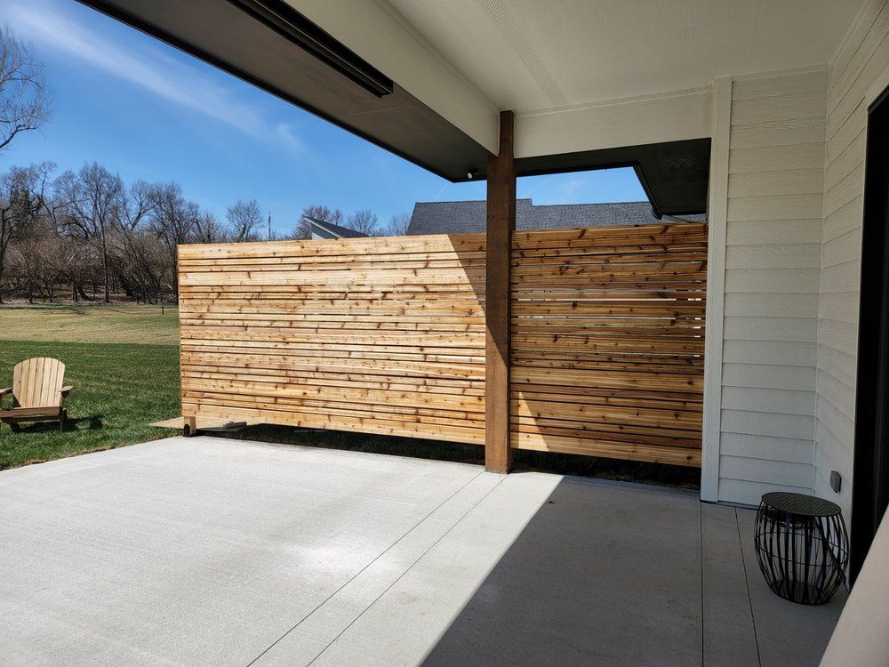 A patio with a wooden fence and chairs