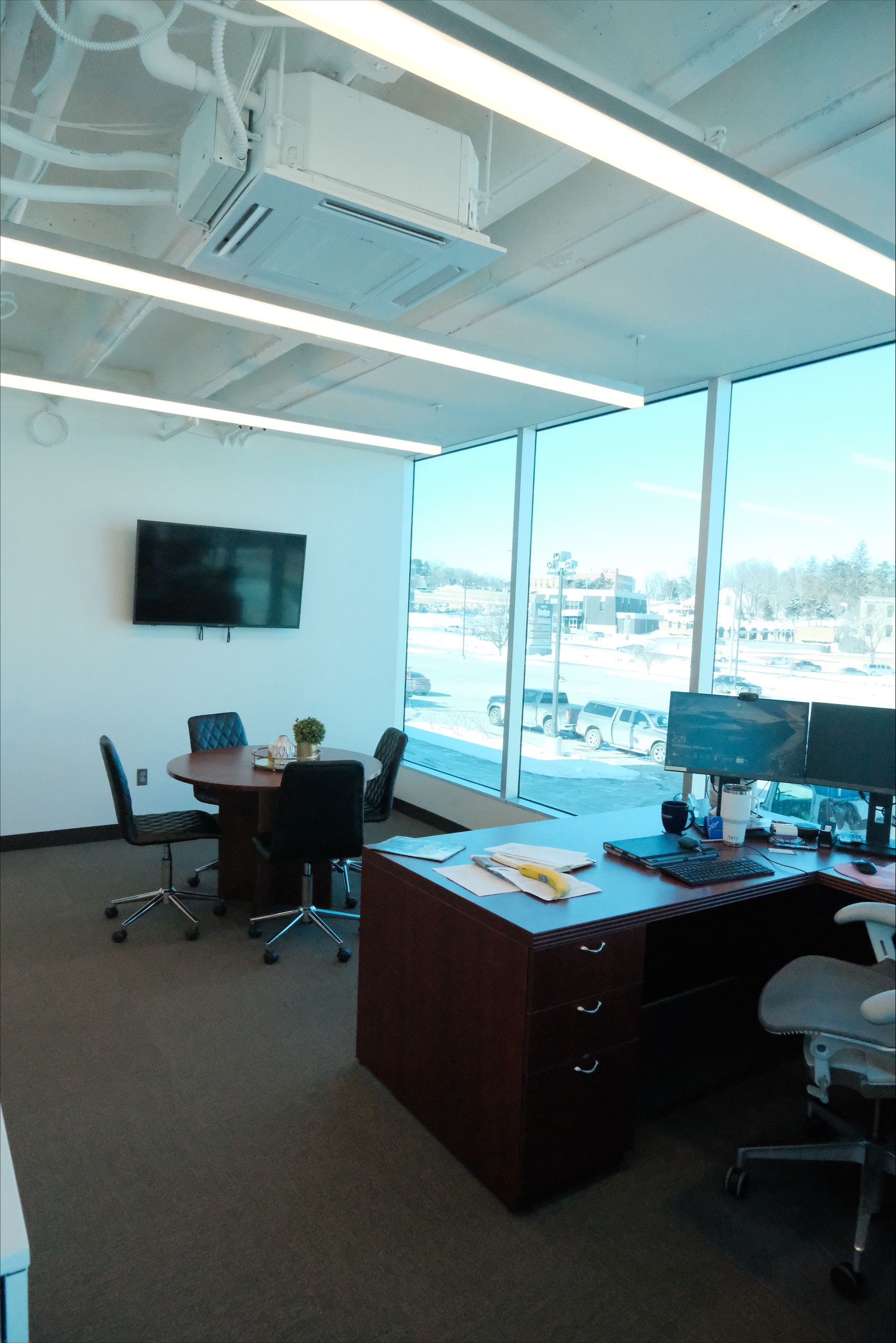 A conference room with a table and chairs and a flat screen tv on the wall.