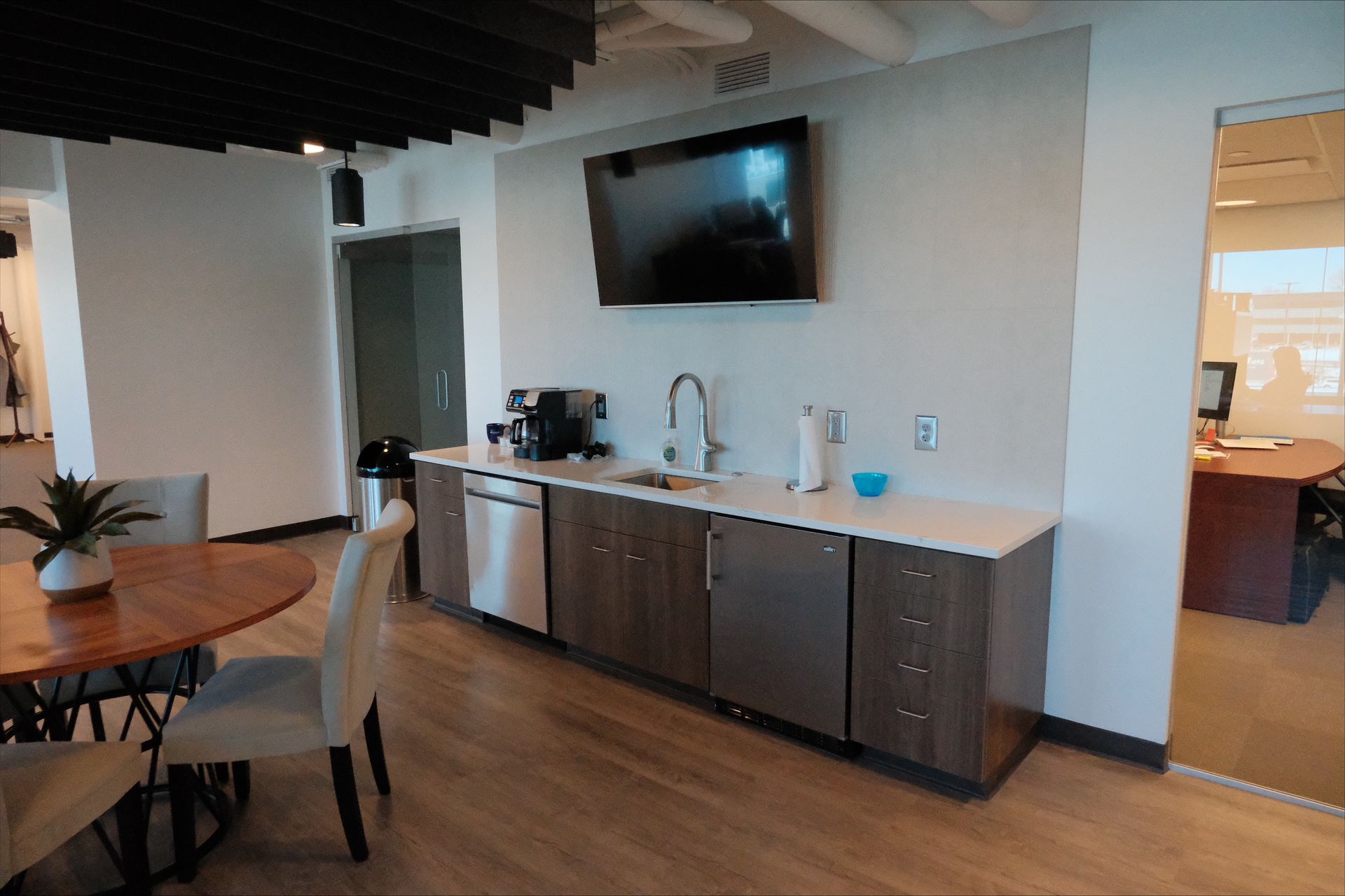 A kitchen with a table and chairs and a flat screen tv on the wall.