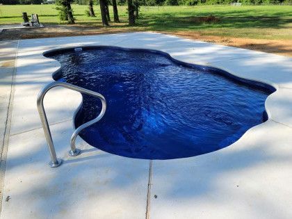 A large blue swimming pool is sitting on top of a concrete patio.