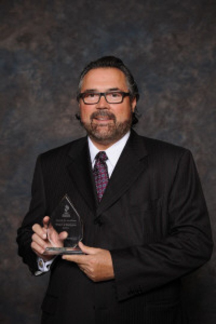 A man in a suit and tie is holding a trophy