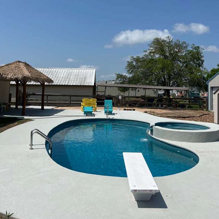 A large swimming pool surrounded by chairs and a gazebo