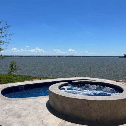 There is a hot tub next to a pool with a view of the ocean.