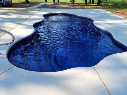 A large blue swimming pool is sitting on top of a concrete patio.