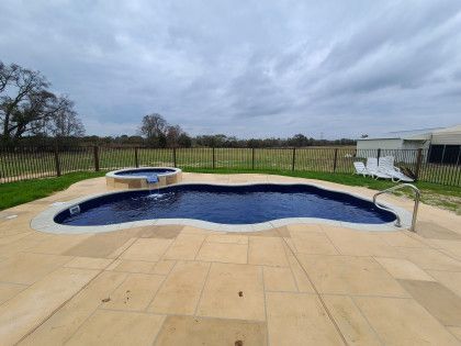 A large swimming pool with a hot tub in the backyard.