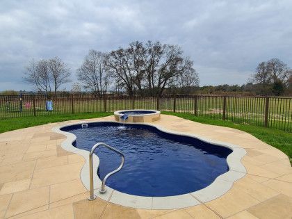 A large swimming pool with a hot tub in the backyard.
