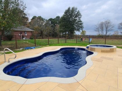 A large swimming pool with a hot tub in the backyard.