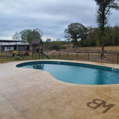A large swimming pool surrounded by trees and a playground