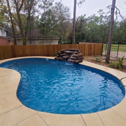 A large swimming pool with a waterfall in the backyard.