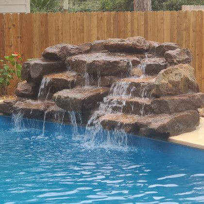 There is a waterfall in the middle of a swimming pool.