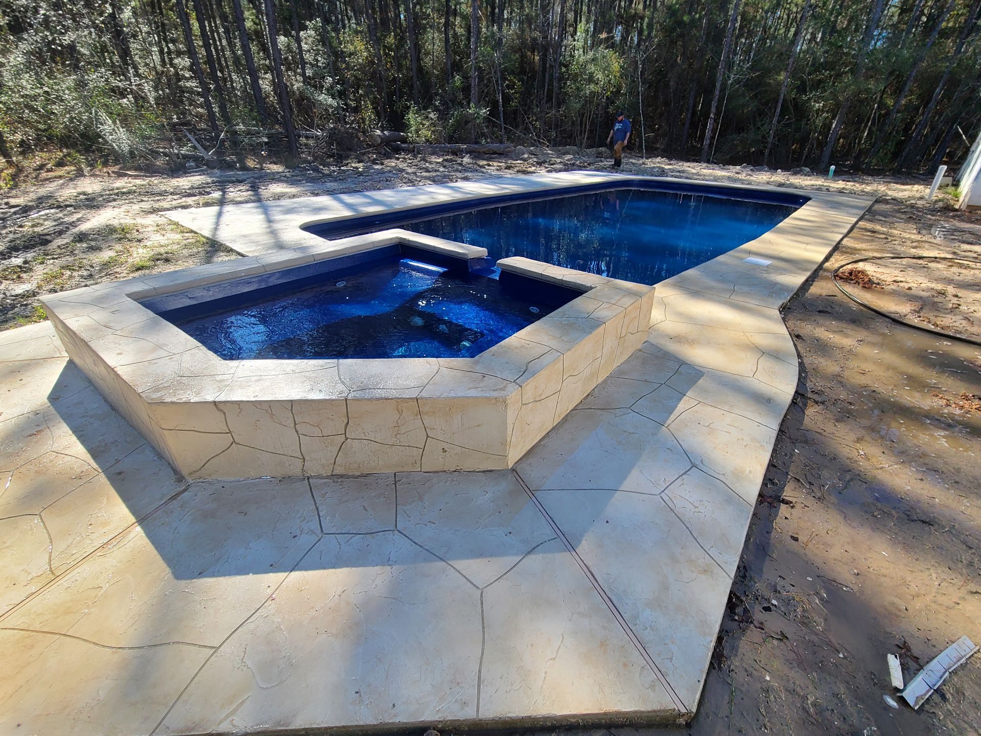 A large swimming pool with a hot tub in the middle of it.