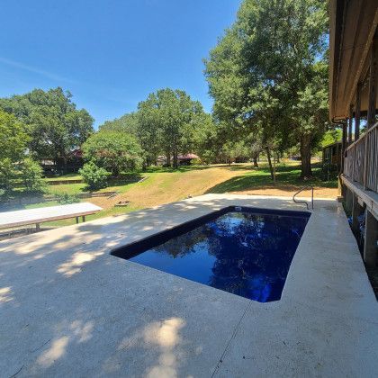 There is a large swimming pool in the backyard of a house.