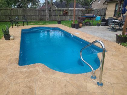 A large swimming pool with a staircase leading to it in a backyard.