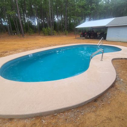 A large swimming pool is sitting in the middle of a dirt field.