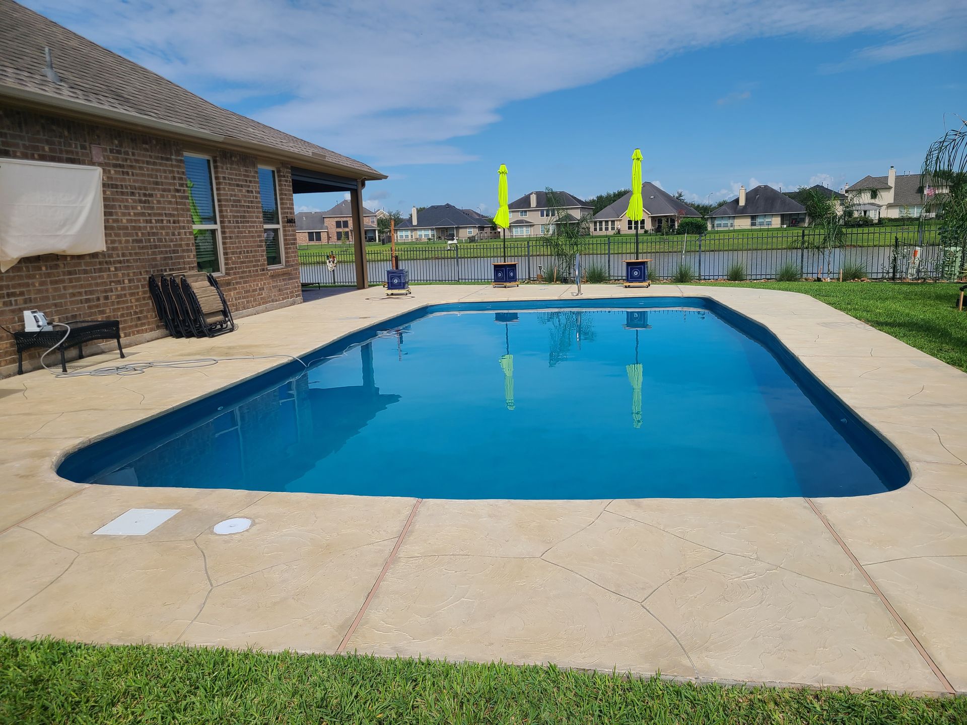 A large swimming pool is in the backyard of a house.