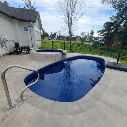 A large swimming pool with a hot tub in the backyard of a house.