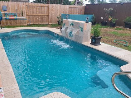 A large swimming pool with a waterfall in the backyard.