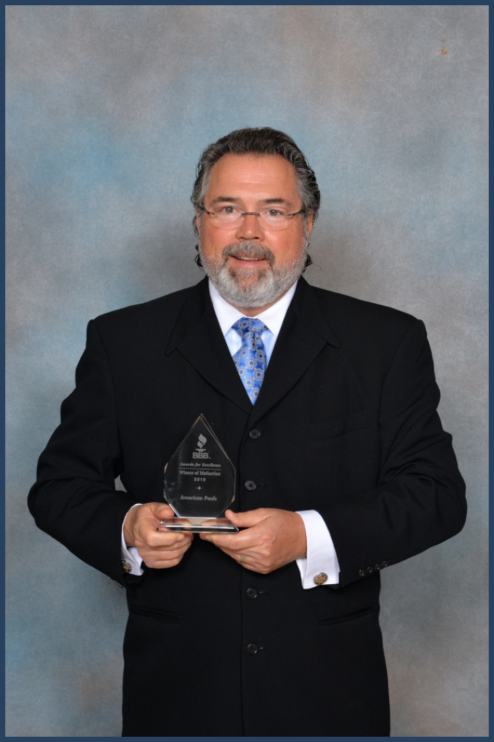 A man in a suit and tie is holding an award