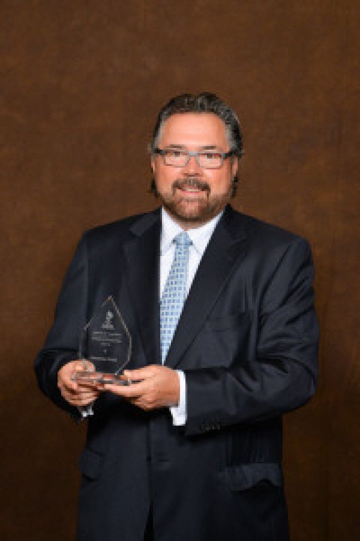 A man in a suit and tie is holding an award