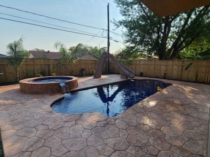 A swimming pool with a slide and a hot tub in the backyard.