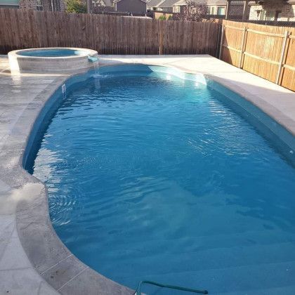 A large swimming pool with a hot tub in the backyard.