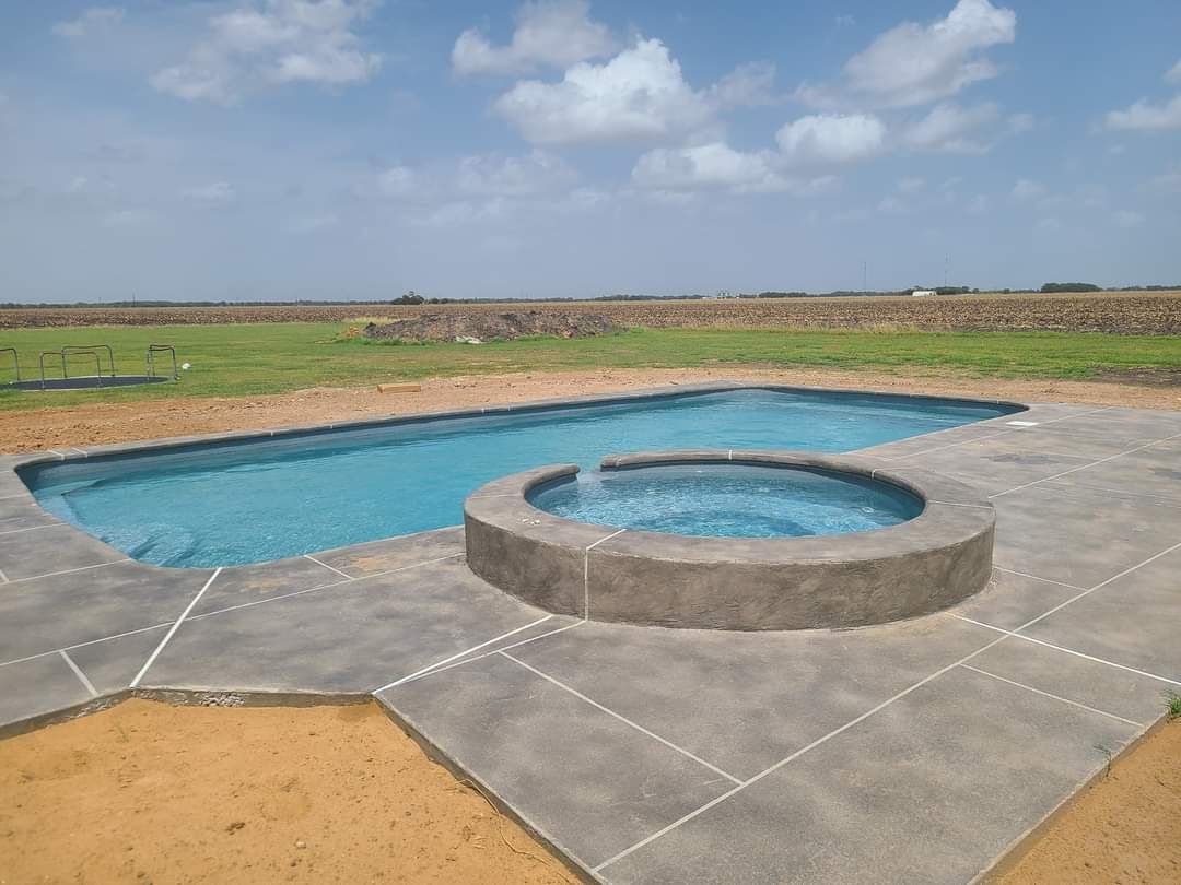 A large swimming pool with a hot tub in the middle of it.