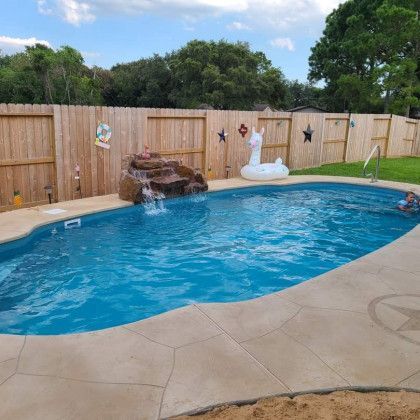 A large swimming pool surrounded by a wooden fence and a swan float.