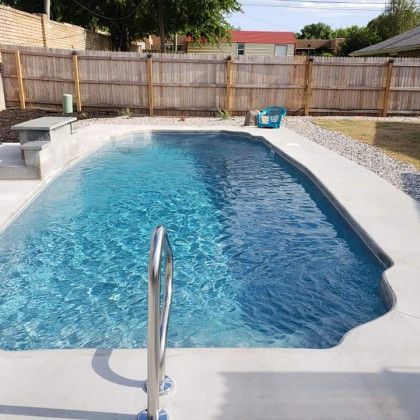 A large swimming pool in a backyard with a wooden fence surrounding it.