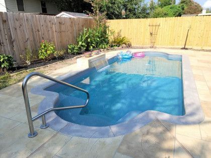 A small swimming pool in a backyard next to a wooden fence.