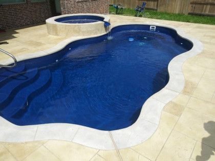 A large swimming pool with a hot tub in the backyard.