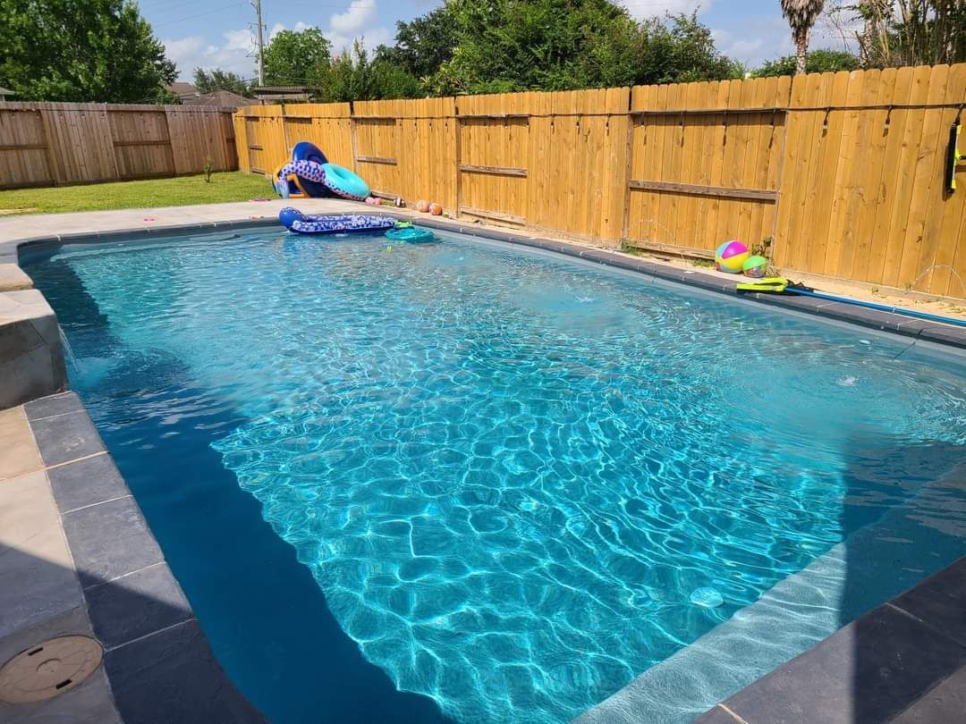 A large swimming pool with a wooden fence surrounding it.