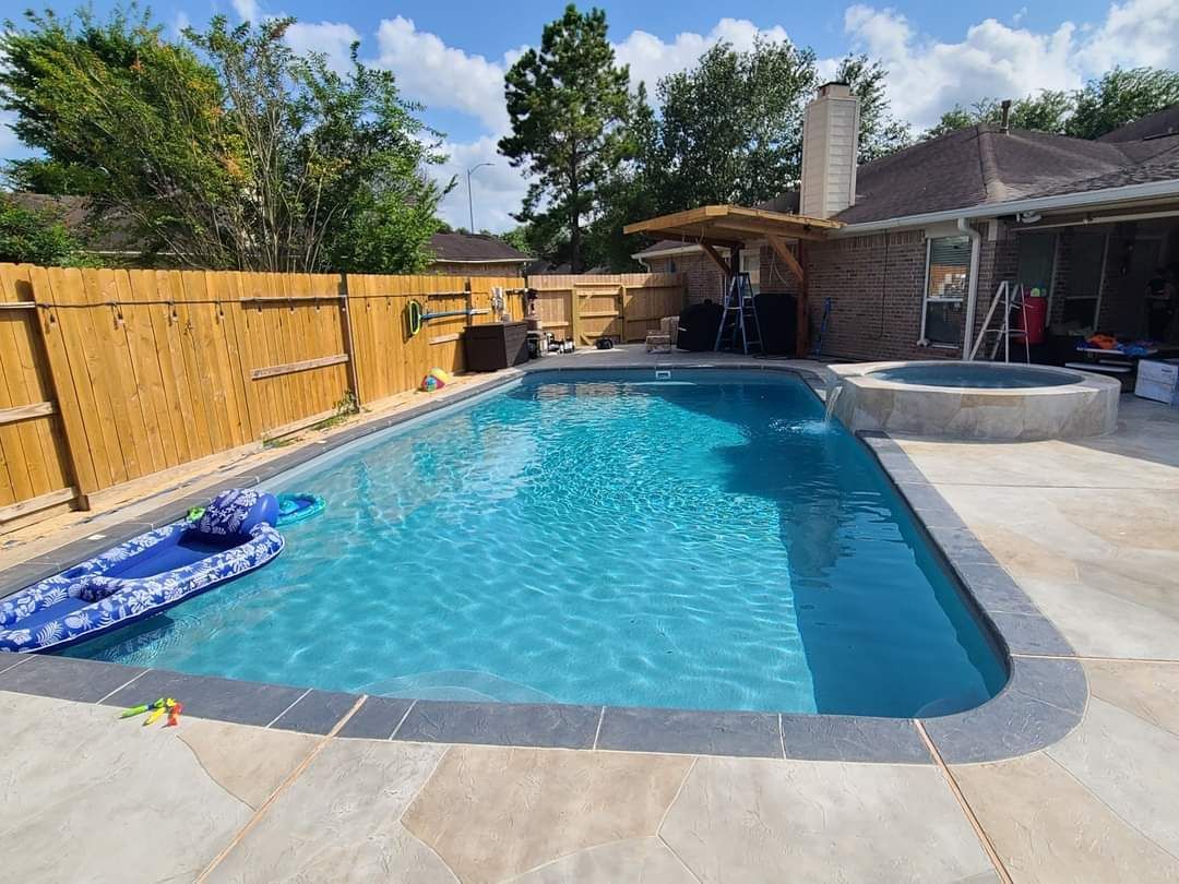 There is a large swimming pool in the backyard of a house.