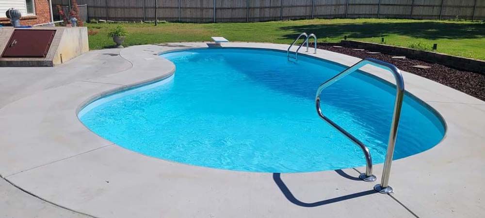 A large swimming pool with a staircase leading to it in a backyard.