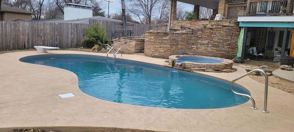 A large swimming pool with a hot tub in the backyard of a house.