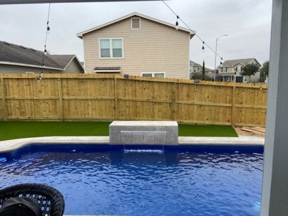 A swimming pool with a waterfall in the backyard of a house.
