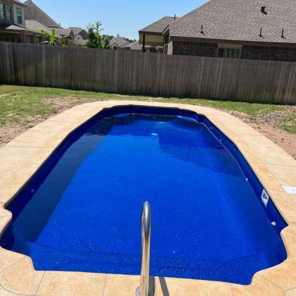 A large blue swimming pool in a backyard next to a wooden fence.