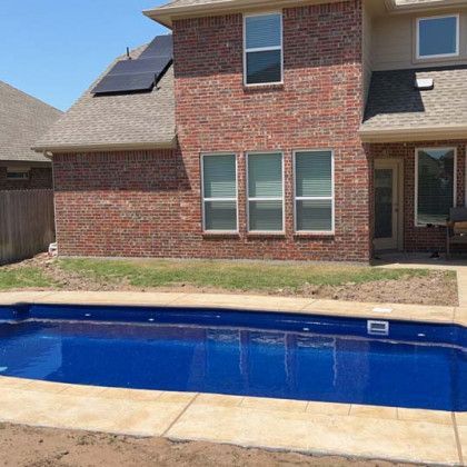 A brick house with a large swimming pool in front of it