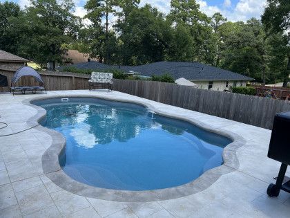 There is a large swimming pool in the backyard of a house.
