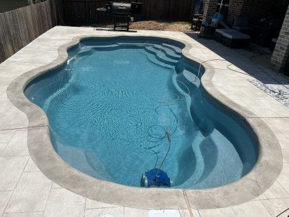 A large swimming pool with stairs and a robotic vacuum cleaner in it.