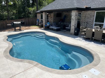 There is a large swimming pool in the backyard of a house.