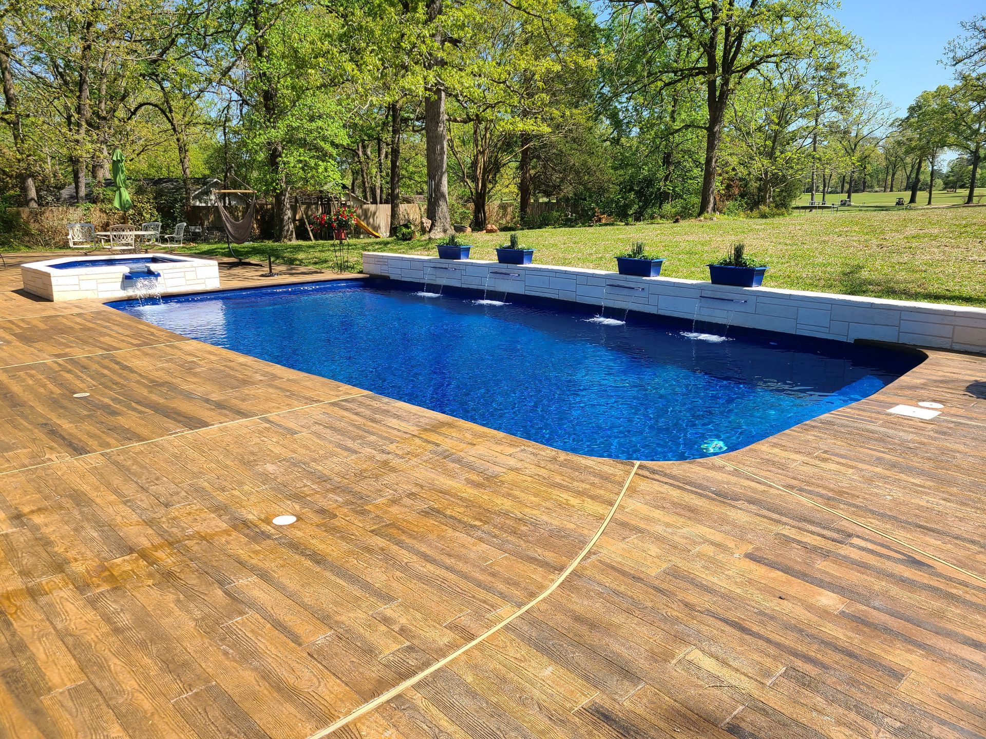 A large swimming pool surrounded by trees and a wooden deck.