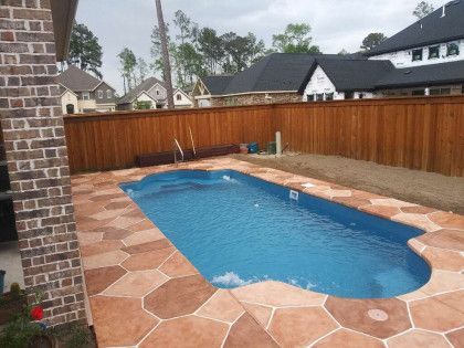 A large swimming pool is surrounded by a wooden fence.
