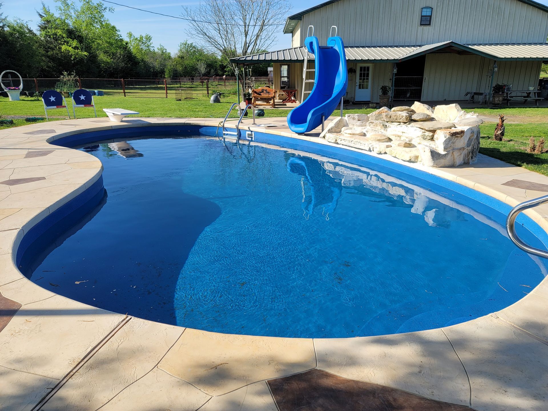A large swimming pool with a blue slide in front of a house