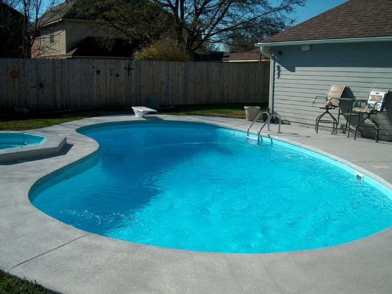 A large blue swimming pool in a backyard next to a house