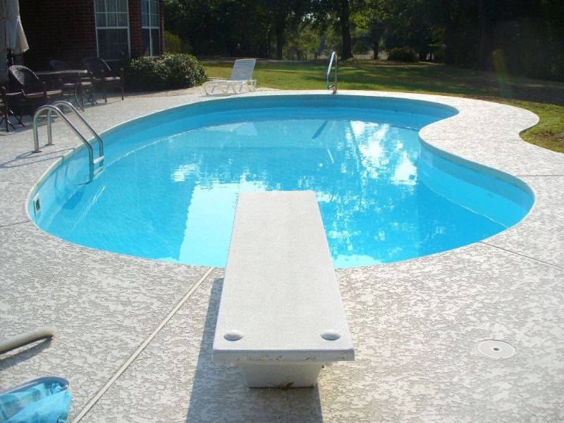 A swimming pool with a diving board in the middle