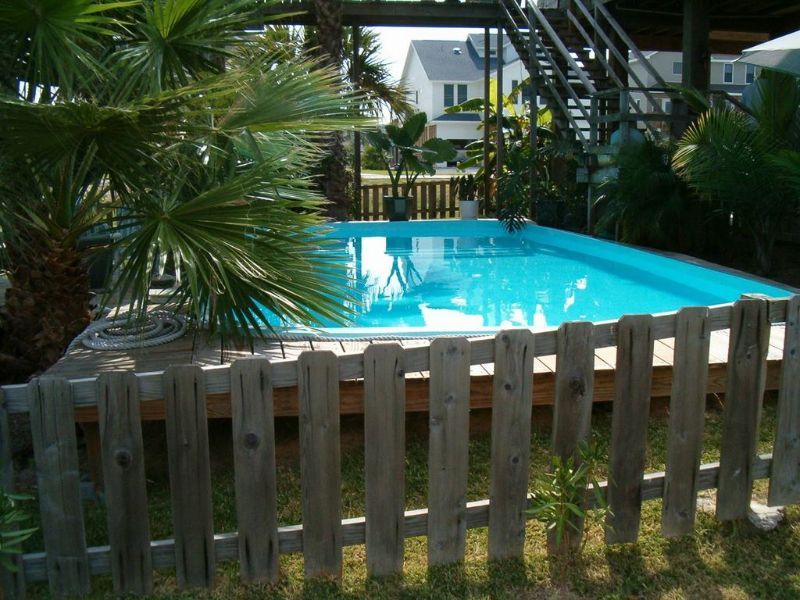 A wooden fence surrounds a large swimming pool