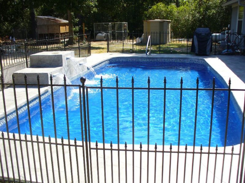 A large swimming pool behind a wrought iron fence