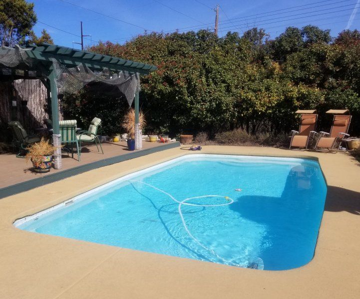 A large swimming pool with a pergola in the background